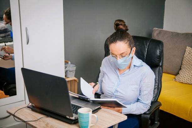 istock woman with a mask on her working from home 1214360906