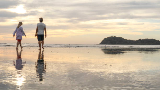 istock Couple walk along beach at sunrise 1214367032