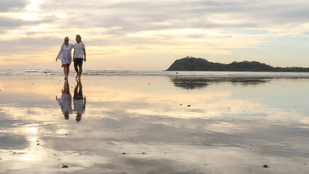 istock Couple walk along beach at sunrise 1214367039