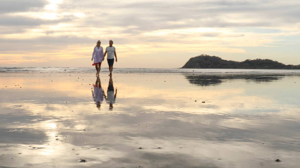 istock Couple walk along beach at sunrise 1214367054