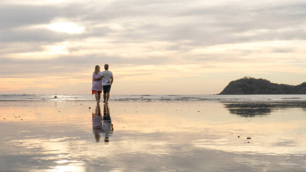 istock Couple walk along beach at sunrise 1214367062