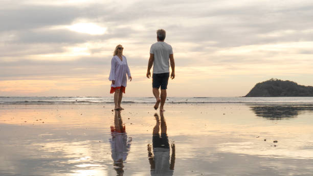 istock Couple walk along beach at sunrise 1214367063