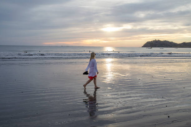 istock Woman walks along beach at sunrise 1214367137