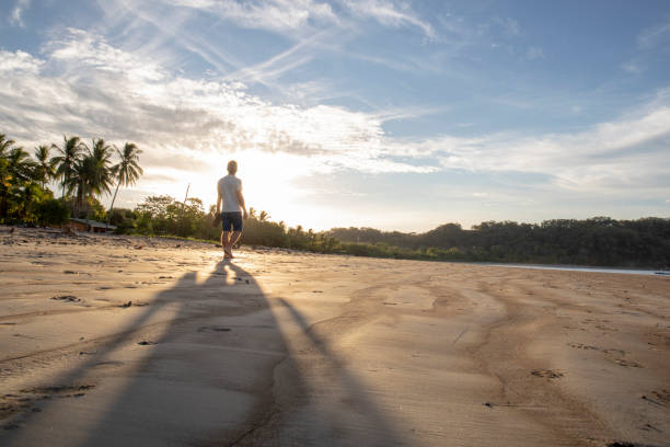 Man walks along beach at sunrise