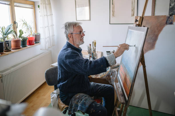 istock Motivated senior painter working on a painting at home 1214373311