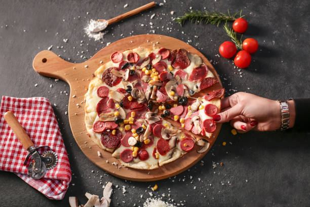 woman taking slice of pepperoni pizza on black table - pepperoni pizza green olive italian cuisine tomato sauce imagens e fotografias de stock