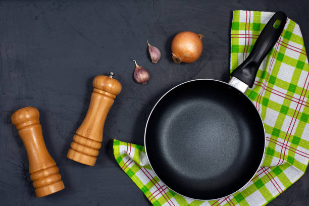 Empty black frying pan or skillet with pepper and sea salt