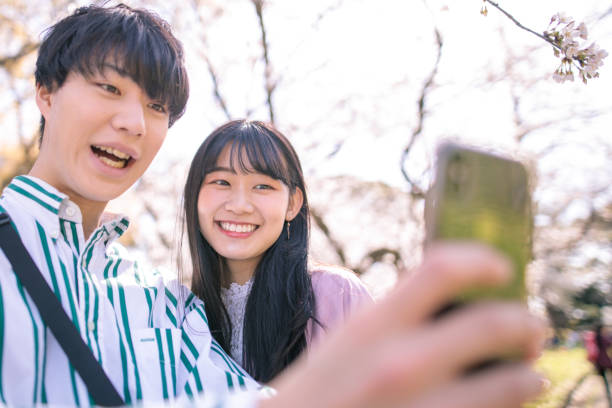 istock Young couple taking selfie picture under cherry blossoms 1214374949