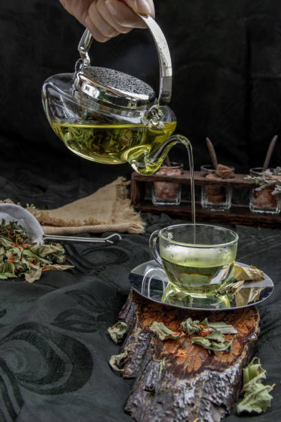A Hot pandan leaf tea with indian marsh fleabane plant leaves and Safflower dried (Saffron substitute) is poured from the glass teapot into a glass with tea herbal and tea leave. A Hot pandan leaf tea with indian marsh fleabane plant leaves and Safflower dried (Saffron substitute) is poured from the glass teapot into a glass with tea herbal and tea leave. Process brewing tea. Selective focus. substitute for saffron stock pictures, royalty-free photos & images