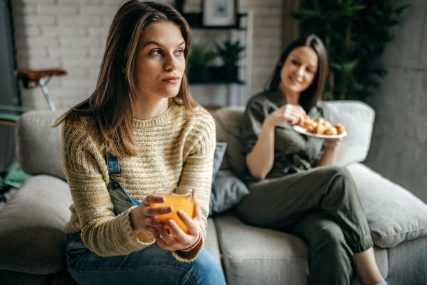 istock Two young women sitting on sofa and relaxing 1214379598