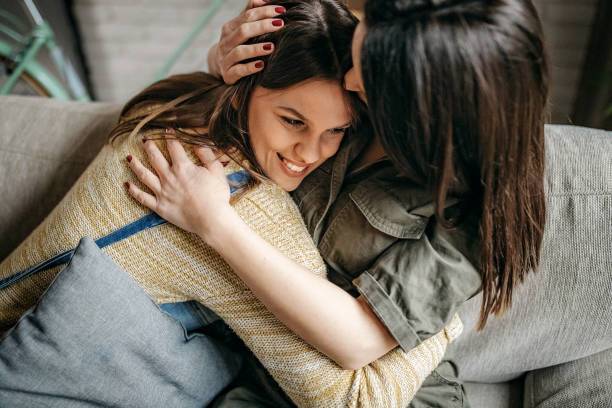 istock Sisters embracing in living room 1214379647