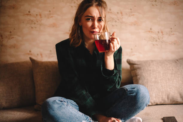 istock Young woman drinking tea while sitting at home 1214387182
