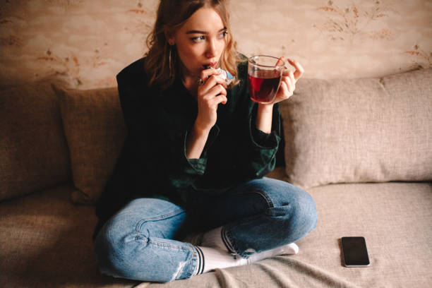 istock Young woman drinking tea while sitting on sofa at home 1214387283