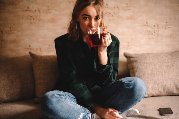 istock Young woman drinking tea while sitting on sofa 1214387305