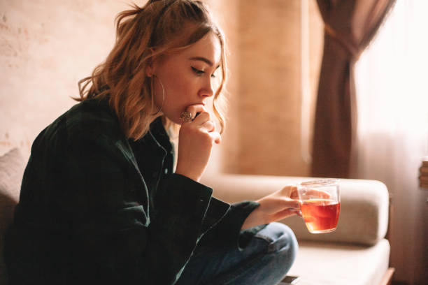 istock Young woman drinking tea while sitting on sofa at home 1214387311