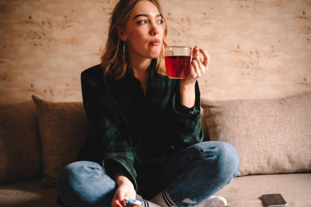 Young woman drinking tea while sitting on sofa at home