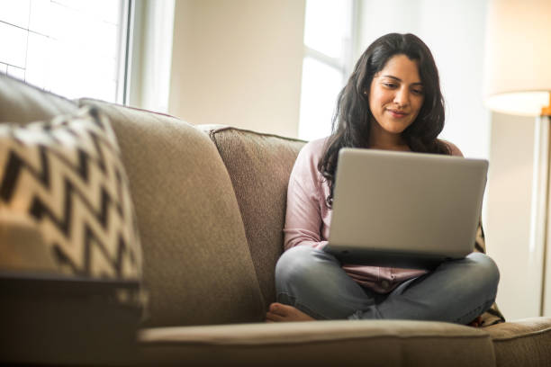 Hispanic woman at home working on a computer. Latin woman working on a laptop doing her budget. latin woman stock pictures, royalty-free photos & images