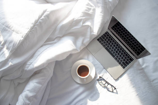 아침에 부드러운 햇빛이 들어오는 침대에서 노트북과 따뜻한 커피의 최고 전망. - hotel hotel room bedroom bed 뉴스 사진 이미지