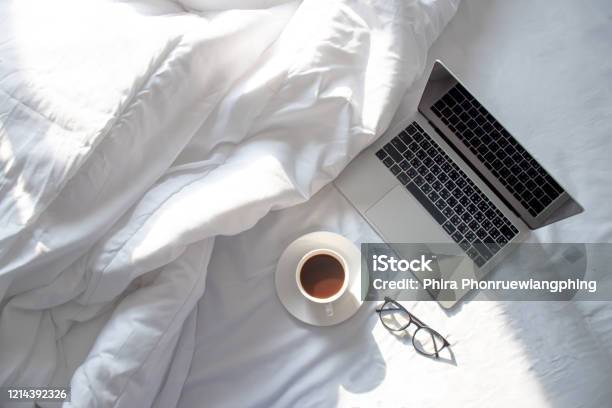 Top View Of Laptop And Hot Coffee In Bed With Soft Sunlight In The Morning Stock Photo - Download Image Now