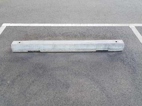 grey cement curb on black asphalt or pavement parking space