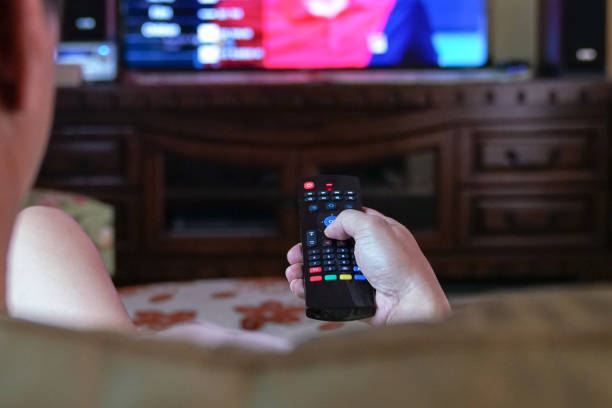 istock Man watching TV at home. Focus on remote control. 1214398703