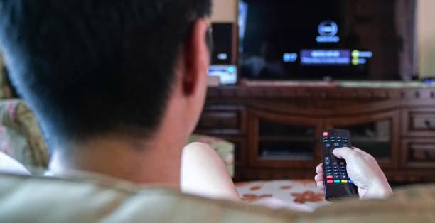 istock Man watching TV. Focus on the hands with remote control. 1214398756