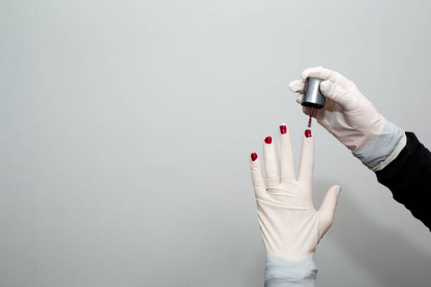 The girl put on a bright manicure shellac on the fingernails. Young girl doing self-care near her desk. There is a laptop, coffee cup, notepad, pen and serving plate on the desk.