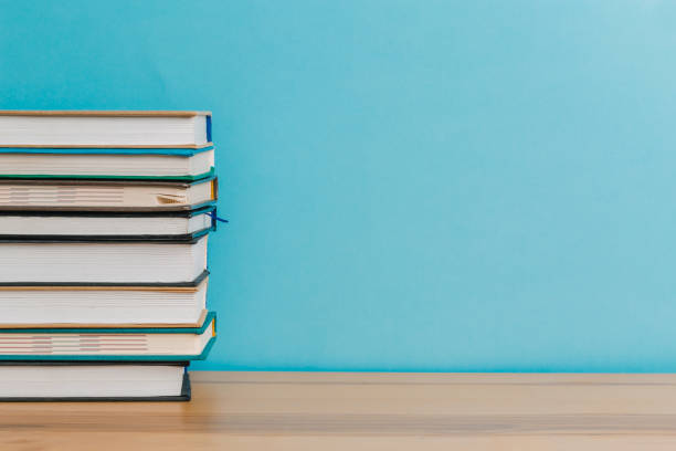 istock Simple composition of hard books, old books on a wooden table and blue background. Stacking books without labels, back to school 1214411981