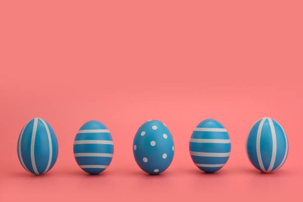 istock A row of five blue decorated Easter eggs on a pink background. 1214412864