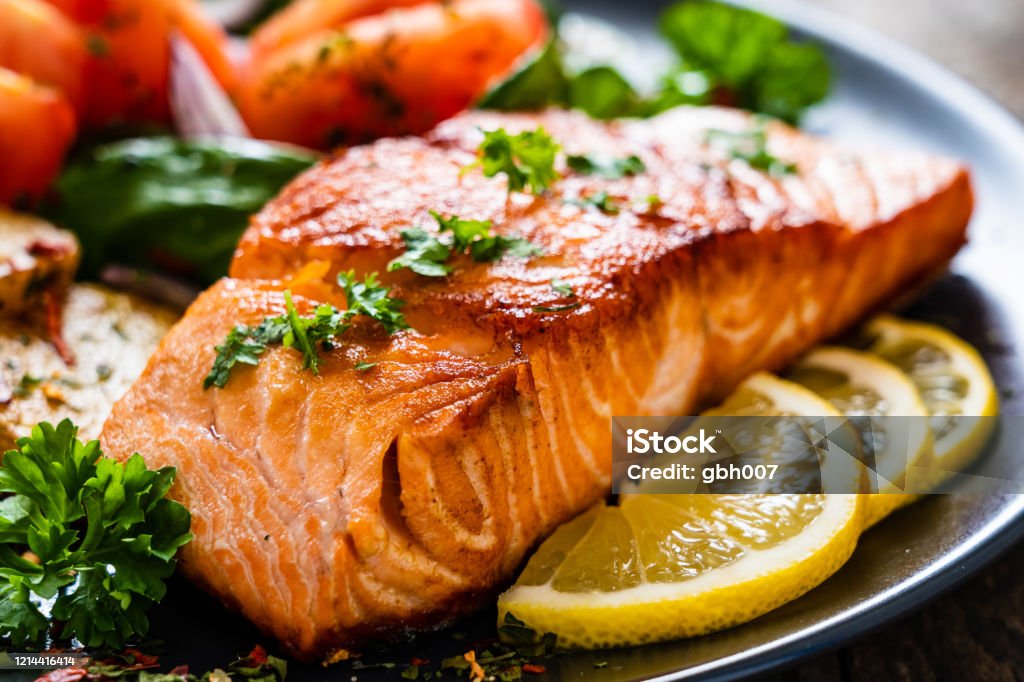 Barbecued salmon, fried potatoes and vegetables on wooden background Salmon - Seafood Stock Photo