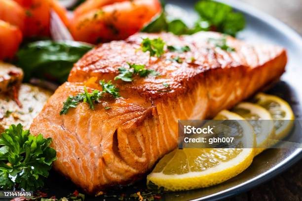 Barbecued Salmon Fried Potatoes And Vegetables On Wooden Background Stock Photo - Download Image Now