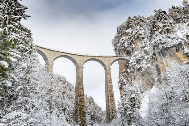 Photo of The Landwasser Viaduct with Railway without famous train at winter, landmark of Switzerland, snowing, river and mountains