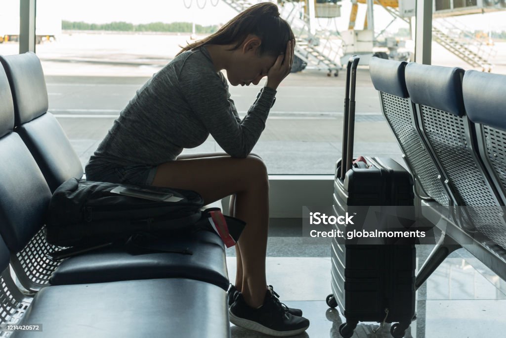 A passenger waiting at the airport terminal stressed out at tired. Passenger waiting at the airport terminal, stressed about missing her flight Fear Stock Photo