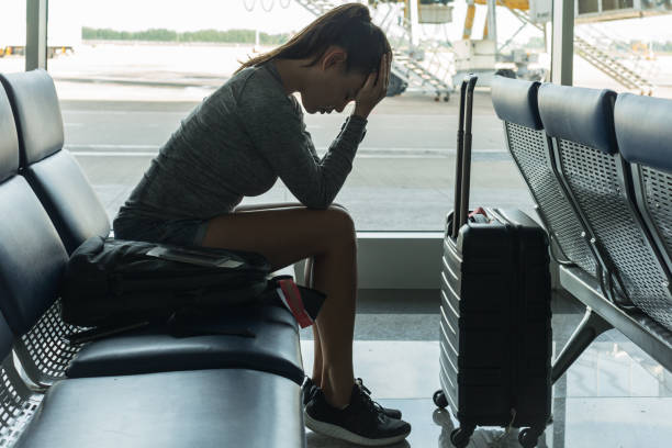 A passenger waiting at the airport terminal stressed out at tired. Passenger waiting at the airport terminal, stressed about missing her flight deportation stock pictures, royalty-free photos & images