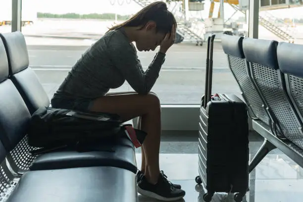 Passenger waiting at the airport terminal, stressed about missing her flight