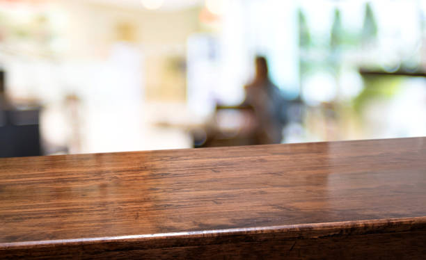 Wood diagonal table with people dinner at restaurant blur background.Empty perspective hardwood bar with blur coffee shop with bokeh light,Mock up  banner for display of product