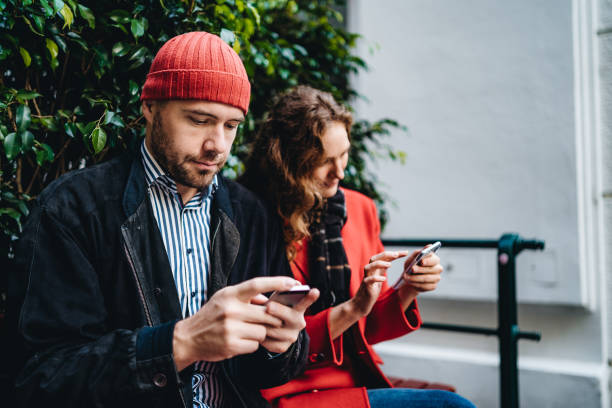 istock Couple sitting outdoors and using mobile phone 1214422547