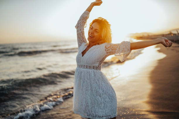 istock Happy woman dancing on beach 1214424496