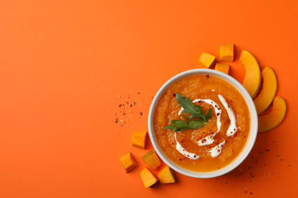 istock Pumpkin cream soup on orange background, top view 1214429152