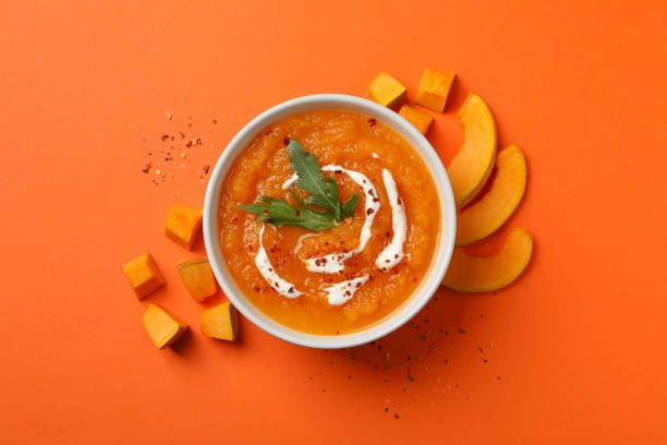 istock Pumpkin cream soup on orange background, top view 1214432694