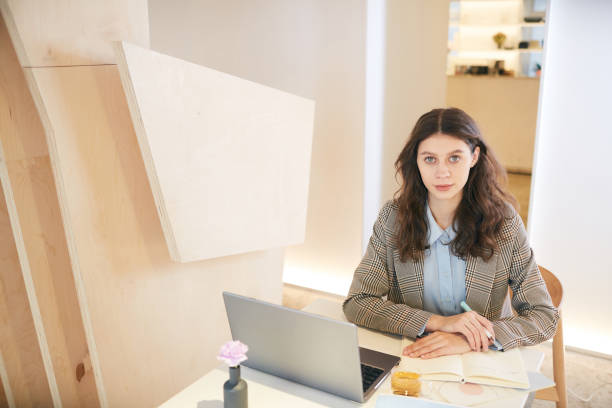 istock Elegant Young Woman at Table in Library 1214432911