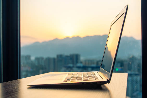 istock Laptop on wood table by window  at sunset 1214433012
