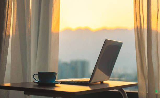 istock Laptop on desk with window sunset 1214434148