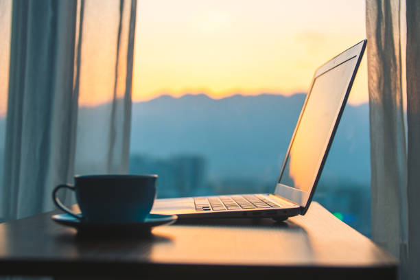 istock Laptop on wood table by window  at sunset 1214434332