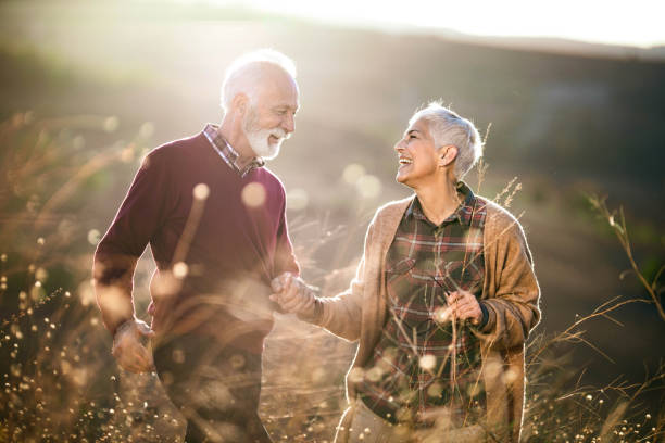 istock Cheerful mature couple talking while walking through tall grass in nature. 1214434419