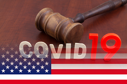 Wooden judge gavel with letters covid19 on table and usa flag. Concept of quarantine and law against covid-19.