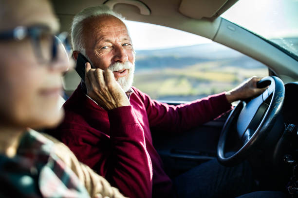 istock Careless senior man talking on cell phone while going on a trip with his wife by car. 1214435622