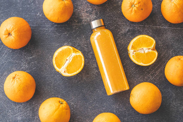 istock Bottle of orange juice and oranges on dark background 1214437621