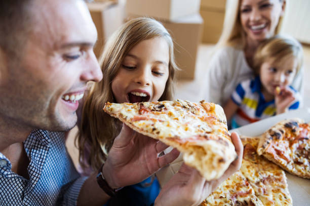 szczęśliwy ojciec i córka jedzą pizzę na lunch po przeprowadzce do nowego domu. - eating food biting pizza zdjęcia i obrazy z banku zdjęć