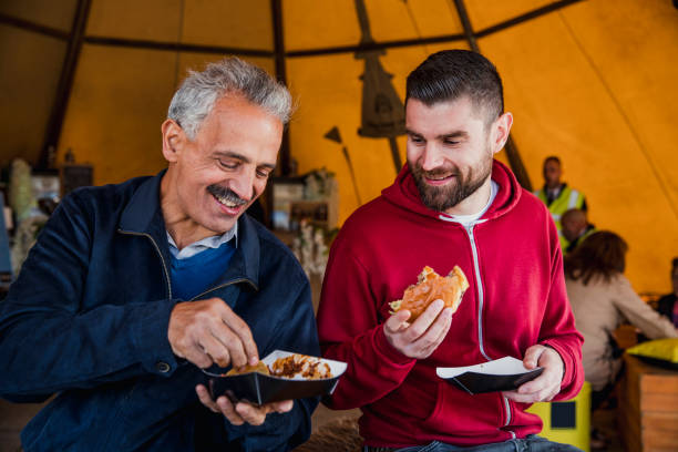 Great Company and Great Food A man and his father-in-law eating burgers together at a food festival in Whitley Bay. food festival stock pictures, royalty-free photos & images